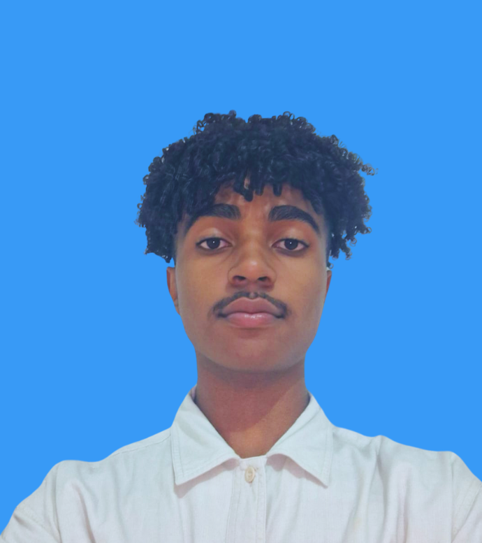 Imagem de Marcio vestindo camisa social branca e sorrindo com os labios sem mostra os dentes, um jovem de pele preta com cabelos cacheados escuros e olhos castanhos